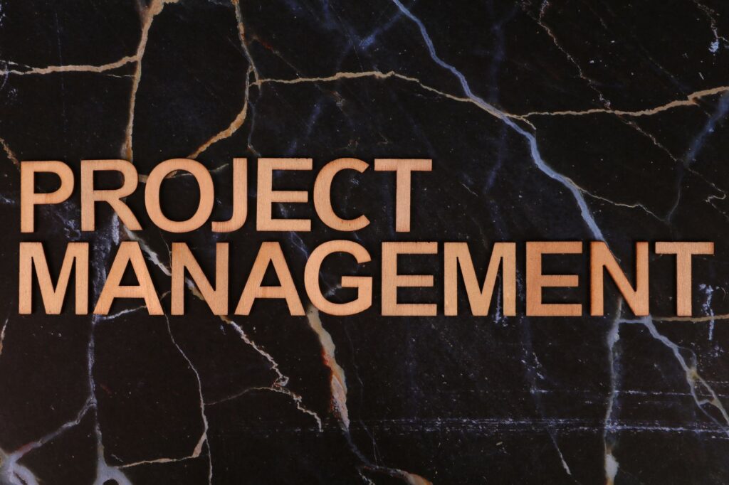 Wooden letters form 'Project Management' on a dark marble surface, perfect for business themes.