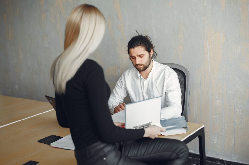 Two colleagues collaborating in a modern office setting, discussing paperwork.