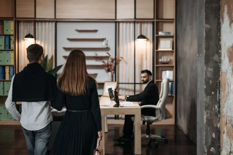 A couple approaches a lawyer in a contemporary office setting for a professional consultation.
